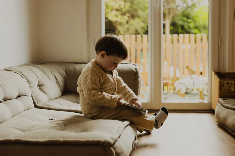 enfant de la creche qui lit pres de la fenetre